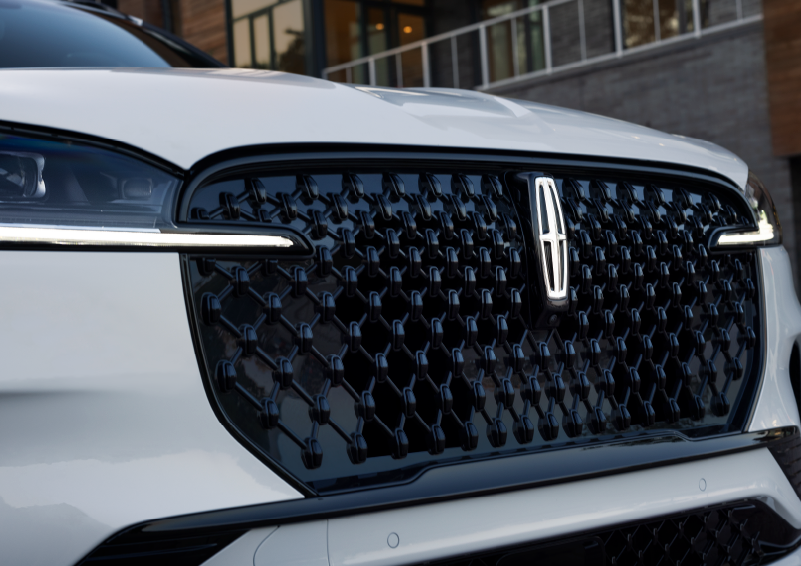 The black grille of a white 2025 Lincoln Aviator® SUV is shown with its fog lights on. | Allan Vigil Lincoln, Inc. in Morrow GA