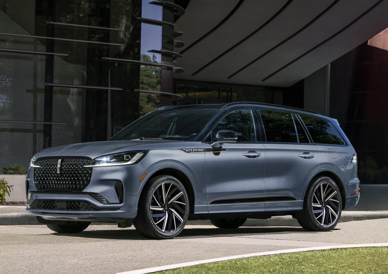 A gray 2025 Lincoln Aviator® SUV is parked outside a modern building showcasing the driver’s side of the vehicle. | Allan Vigil Lincoln, Inc. in Morrow GA
