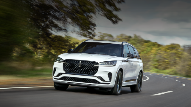 A white 2025 Lincoln Aviator® SUV is being driven down a road lined with trees. | Allan Vigil Lincoln, Inc. in Morrow GA