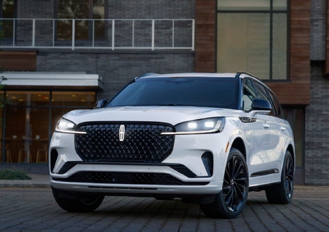A 2026 Lincoln Aviator® Reserve model is shown with the available Jet Appearance Package parked near a restaurant. | Allan Vigil Lincoln, Inc. in Morrow GA