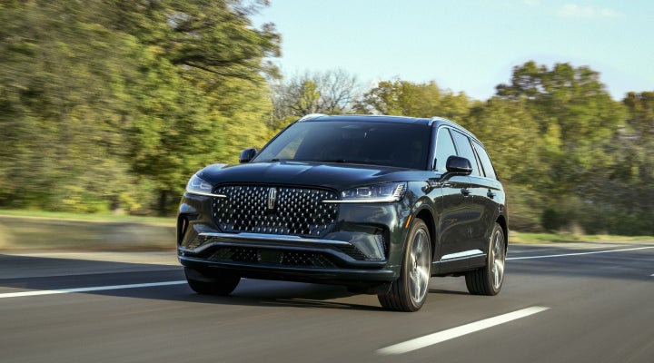 A 2026 Lincoln Black Label™ Aviator® SUV is being driven down a road lined with trees. | Allan Vigil Lincoln, Inc. in Morrow GA