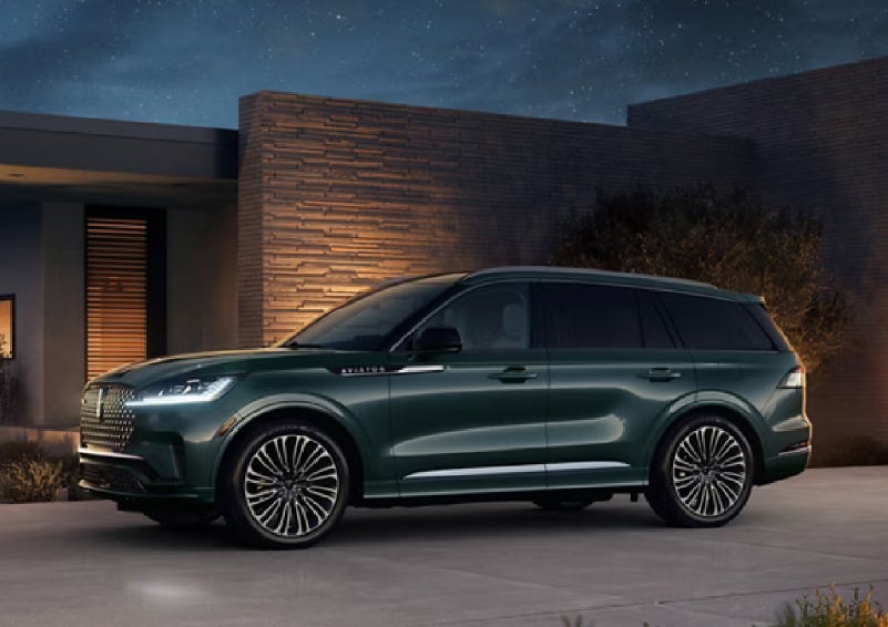 A green 2027 Lincoln Aviator® SUV is parked outside a contemporary home. | Allan Vigil Lincoln, Inc. in Morrow GA