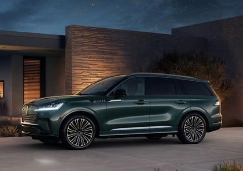 A green 2027 Lincoln Aviator® SUV is parked outside a contemporary home. | Allan Vigil Lincoln, Inc. in Morrow GA
