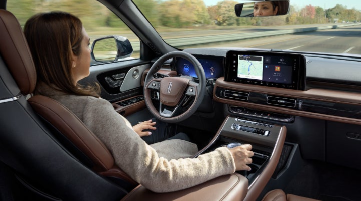 A 2027 Lincoln Aviator® SUV is being driven hands-free on a highway lined with trees. | Allan Vigil Lincoln, Inc. in Morrow GA