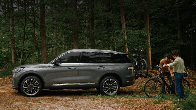 A father and son load e-bikes on a bike rack attached to a 2027 Lincoln Aviator® SUV. | Allan Vigil Lincoln, Inc. in Morrow GA
