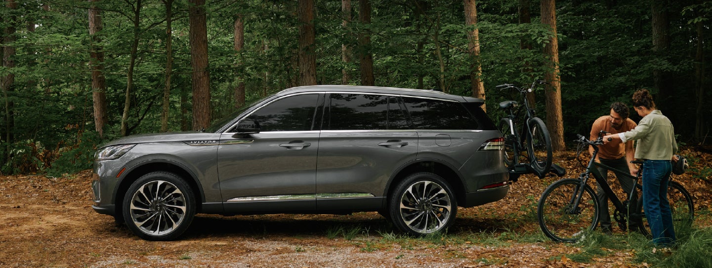 A father and son load e-bikes on a bike rack attached to a 2027 Lincoln Aviator® SUV. | Allan Vigil Lincoln, Inc. in Morrow GA